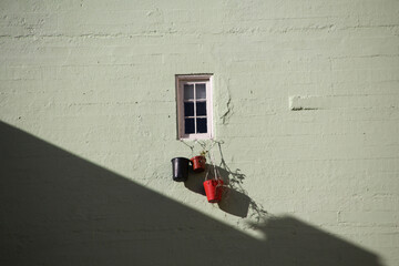 Poster - Closeup shot of a cute small window with three plant pots hanging on it under the sun