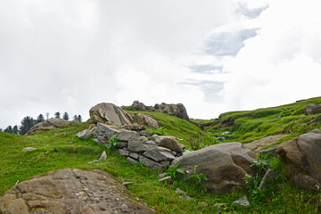 Poster - Scenic view of a green rocky meadow under the cloudy sky