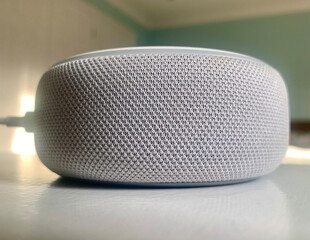 Sticker - Closeup shot of a smart speaker on a white surface in a room with green and white walls