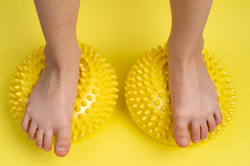 children's feet with a yellow balancer on a light yellow background, treatment and prevention of flat feet, valgus deformity of the foot