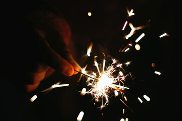 Poster - Closeup shot of holding illuminated sparklers and celebrating the Happy New Year