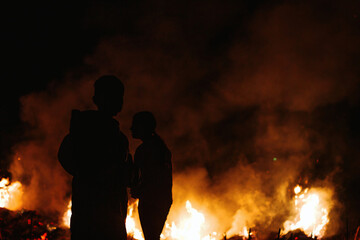 Canvas Print - Silhouette shot of the children against fire in the field at night