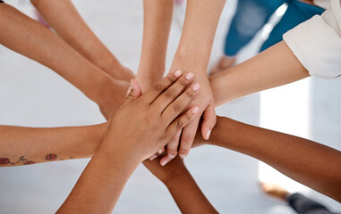 Were all in this together. Cropped shot of a group of unrecognizable businesspeople joining hands together in a huddle inside an office.