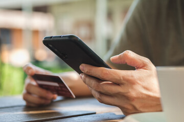 Poster - woman shopping online with credit card at coffee shop in outdoor.close up hand holding smartphone