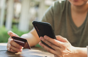 Poster - woman shopping online with credit card at coffee shop in outdoor.close up hand holding smartphone