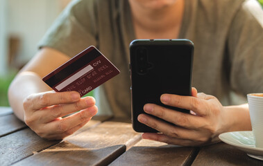 Poster - woman shopping online with credit card at coffee shop in outdoor.close up hand holding smartphone
