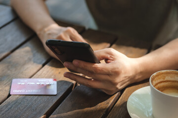Poster - woman shopping online with credit card at coffee shop in outdoor.close up hand holding smartphone