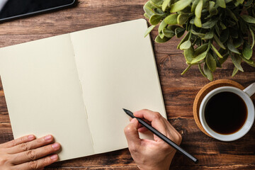 Poster - top view hand writing on notebook and coffee cup on wood office desk
