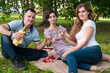 © Beliakina Ekaterina - Two girls and a man are having a picnic in the summer in the park