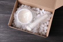 Mortar And Pestle With Bubble Wrap In Cardboard Box On Dark Wooden Table