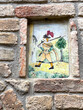 Ceramic painting of a medieval soldier inset in a wall in San Gimignano, Italy