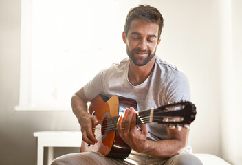 Poster - Honing his musical talent. Shot of a handsome young man playing a guitar at home.