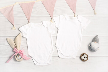 Wall Mural - Two white baby bodysuit mockup with Easter decor on white wood background. Easter eggs and gnome with rabbit ears