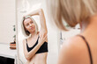 Middle aged woman looking herself in a mirror while doing breast self-examination