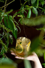 Hand is holding a glass of lemon cocktail outside