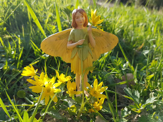 Poster - Closeup of a miniature gardening fairy statue near a Ficaria verna