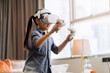 © whyframeshot - exiting asian child female enjoy metaverse gaming with wearable vr headset with control handle playing sport gaming online in living room at home,home technology female daughter using vr technology