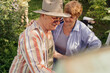 © diignat - HAPPY SENIOR COUPLE spend time together in their garden or nature. Man is painting, love, romance, communication. Growing old beautifully together. Vibrant green garden