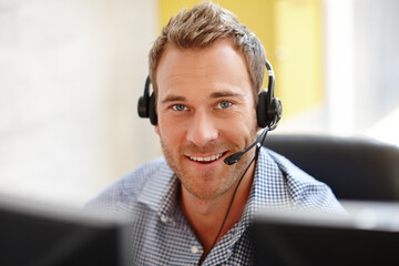 He knows how to sell your product. Portrait of a male customer service representative at his computer.