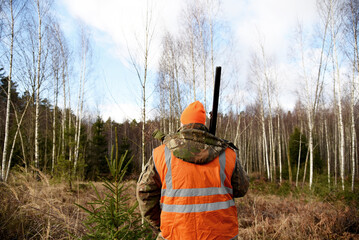 Hunter while hunting wild animals. Hunters track down a wild boar or elk in the forest. Hunter during hunting in forest. Hunters with gun and rifle on hunting in the fall season.