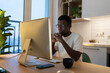 © DimaBerlin - Concentrated african software developer work on new application from home. Focused young coder programmer looking on computer screen. Serious freelance programmer millennial using pc occupied remotely