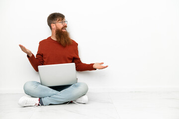 Young reddish caucasian man with laptop isolated on white background with surprise expression while looking side