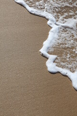 Wall Mural - A wave rolls up the sand at the beach with Copyspace