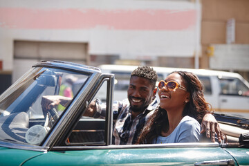 No road is long with good company. A happy young couple driving in a convertible on a bright summers day.