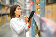 © Nay - Asian female is holding tablet and checking carton of product in furniture store