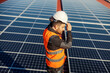 © dusanpetkovic1 - A worker putting helmet while standing on the roof with solar panels.