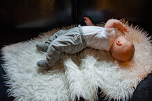 Baby Boy In White Shirt And Grey Pants On White Rug, Playing With Toy