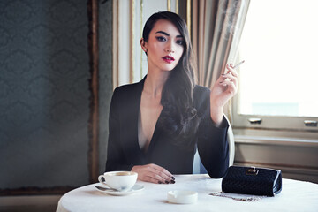 Wall Mural - Luxury and style. Shot of a woman smoking a cigarette in a luxurious setting wearing classicly elegant attire.