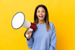 Caucasian girl isolated on yellow background holding a megaphone and with surprise expression
