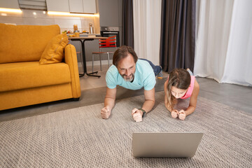 Wall Mural - Adult man doing plank exercise with teenager in living room