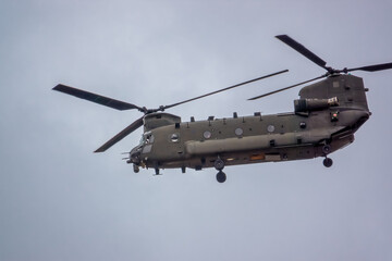 Wall Mural - close up of an RAF Chinook tandem-rotor CH-47 helicopter flying fast and low in a cloudy blue grey sky on a military battle exercise, Wilts UK