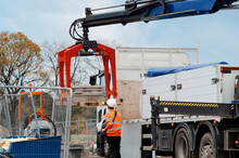 Construction materials delivered on site and being offloaded by hydraulic truck mounted crane