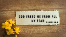 Top View Of Bible Verse God Freed Me From All My Fear. Yellow Flower And Wooden Background.