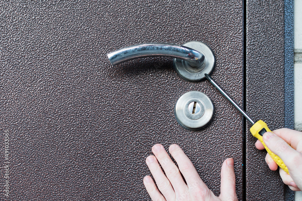 Handyman installing lock in metal door. Checking lock for operability ...
