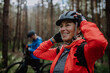© Halfpoint - Senior couple bikers putting on cycling helmet outdoors in forest in autumn day.