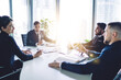 © BullRun - Experienced group of successful employees collaborating at meeting table discussing business executive information during brainstorming in office interior, male and female professionals talking