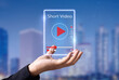© panuwat - Short Video marketing concept.Man hands holding virtual short video player with blurred city as background