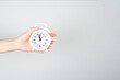 © Alexa Mat - Time management, punctuality, awakening concept. Hand holding alarm clock on light background.