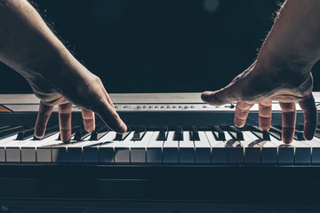 Wall Mural - Male hands play the piano keys in the dark.