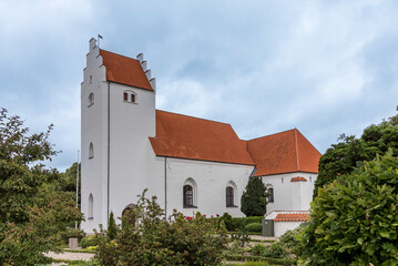 white scandinavian church with a tall tower against the blue sky