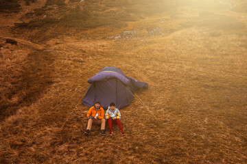 Two tourists sitting near a tent under Mount Hoverla, lunch after a walk.