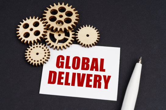 On the black surface are gears, a pen and a business card with the inscription - Global delivery