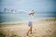 © Cavan Images - Girl waves scarf along the beach shore