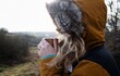 © Cavan Images - woman drinking hot drink on a cold day hiking