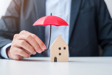 Wall Mural - Businessman hand holding red Umbrella cover wooden Home model. real estate, insurance and property concepts