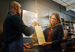 © Thurstan H/peopleimages.com - Another happy shopper. Cropped shot of a cashier passing on a shopping bag to a customer.